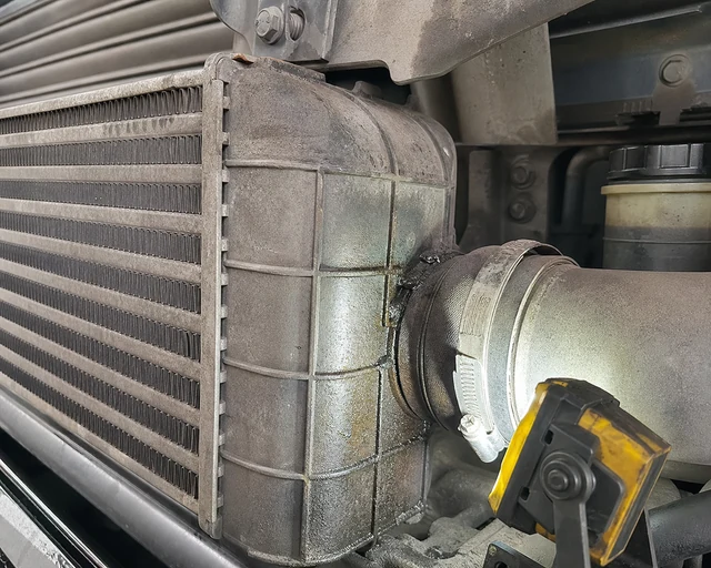 Petă de ulei &icirc;n jurul cusăturii rezervorului de la capătul răcitorului de aer de &icirc;ncărcare a camionului diesel și a conexiunii conductei